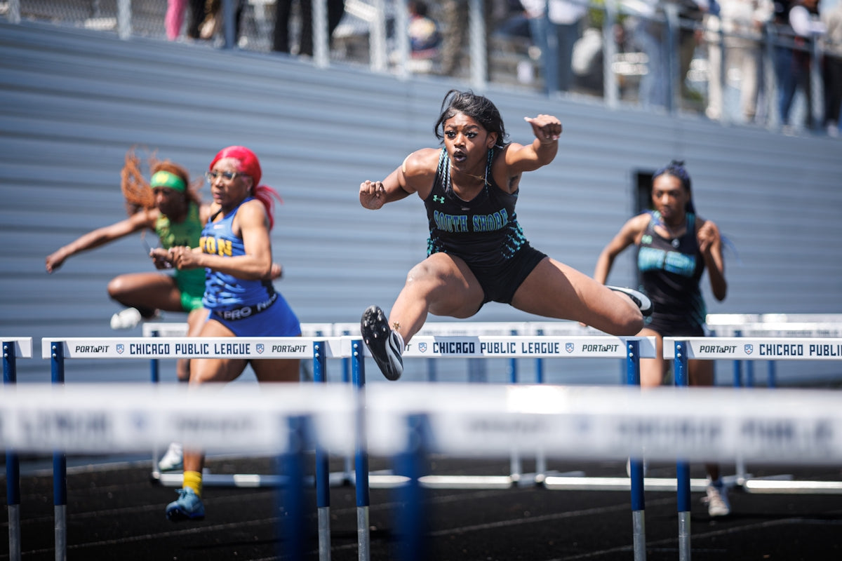 A female athlete hurdles during a race.